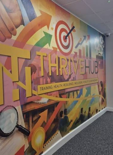 Photo of a wall at Thrive Luton with the hub's logo, banner and other iconic designs.