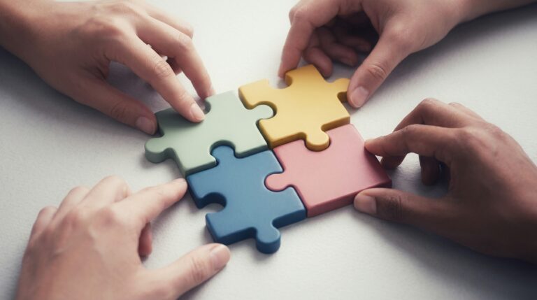 Hands connecting colourful puzzle pieces together