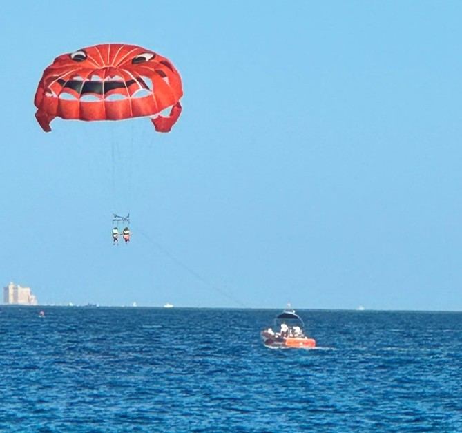Image of the sea, with a boat pulling a parasailer.
